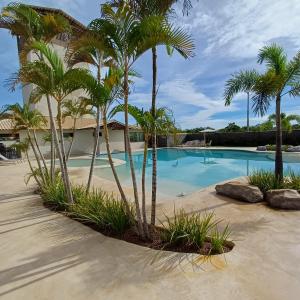 a swimming pool with palm trees in front of a building at Kite House Lençóis in Santo Amaro