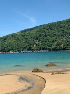 a view of a beach with a mountain in the background at vista mar suite luxo in Angra dos Reis