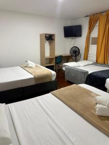 a hotel room with three beds and a flat screen tv at Travesía Quindiana in Filandia