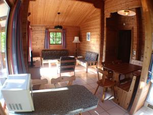 a living room of a log cabin with a table and chairs at Le Havre Sylvestre Séjour nature avec piscine in Mauroux