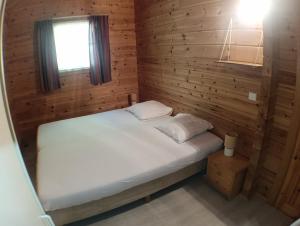 a bed in a wooden room with a window at Le Havre Sylvestre Séjour nature avec piscine in Mauroux +32 photos