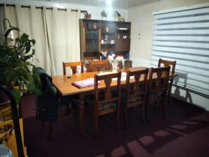 a wooden dining room table with wooden chairs at Hospedaje Domiluis in Coihaique