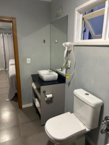 a bathroom with a white toilet and a sink at pousada das manas in Torres