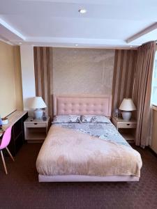 a bedroom with a large bed with two tables and two lamps at Suites Edificio Akros in Quito
