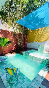 a swimming pool with a chair and an umbrella at Casa Mandala Canoa Quebrada in Aracati