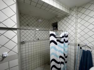 a white tiled shower with a blue and white towel at Ap FIG Garanhuns in Garanhuns