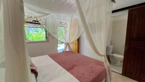 a bedroom with a canopy bed with a window at Biribandos Rooms - a 300 metros do Quadrado e 900 metros das praias in Trancoso