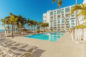 a resort with a pool and palm trees and a building at Santo Domingo Bay Convention Resort & Casino in Boca Chica