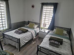 a bedroom with two beds and two windows at Downtown apartment next to highway netflix+wifi in Edmundston