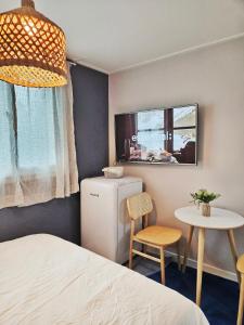 a room with a bed and a refrigerator and a table at The YoGwan in Suwon