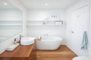 a white bathroom with a tub and a sink at Raglan West Cottage, Surf Side Escape in Raglan +7 photos