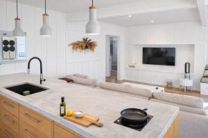 a kitchen and living room with a sink and a couch at Raglan West Cottage, Surf Side Escape in Raglan