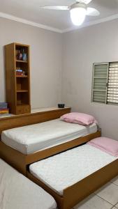 two beds in a bedroom with pink and white sheets at Casa Versátil in Ribeirão Preto