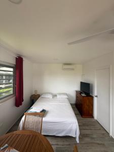 a bedroom with a bed and a table and a window at Tuava - Mirimiri Lodge in Ataiti