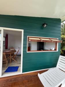 a house with a green wall with a table and chairs at Tuava - Mirimiri Lodge in Ataiti