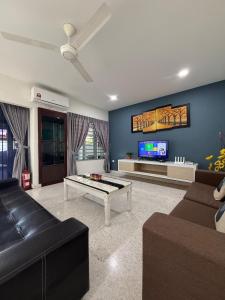 a living room with a couch and a tv at Ipoh Garden 4BR 10Pax in Ipoh