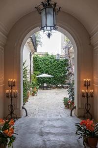 an archway with a patio with an umbrella and plants at Palazzo Degli Antoci in Ragusa