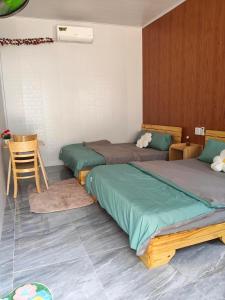 a room with two beds and a table and a chair at Sơn Hà homestay in Ấp Bình Hưng
