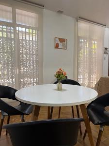a white table and chairs in a room with windows at Casa amplia 3 dormitorios, 2 baños - Smart TV 50" - Entrada Autónoma - Pileta de Verano in Mendoza