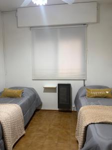 a room with two beds and a window and a fan at Casa amplia 3 dormitorios, 2 baños - Smart TV 50" - Entrada Autónoma - Pileta de Verano in Mendoza