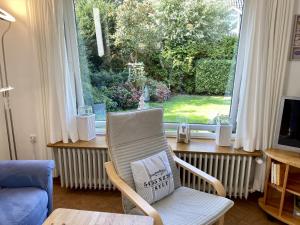 a living room with a chair in front of a window at Lerchenweg Bungalow in Westerland