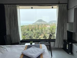 a bedroom with a large window with a bed and a table at Hotel SERENE PRAIA in Visakhapatnam