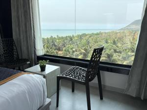 a bedroom with a chair in front of a large window at Hotel SERENE PRAIA in Visakhapatnam +28 photos