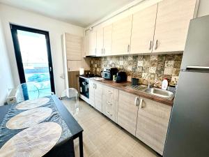 a kitchen with a table and a sink and a refrigerator at DAV apart in Otopeni