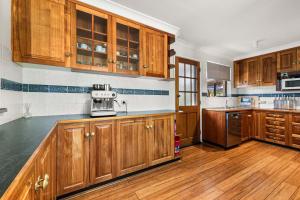 a kitchen with wooden cabinets and wooden floors at Bendalong - Rural Retreat, Short Drive to CBD in Orange