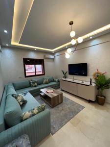 a living room with a blue couch and a flat screen tv at Oasis Gueliz Center Marrakech in Marrakesh