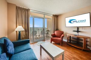 a living room with a blue couch and a tv at Direct Oceanfront Unit Amazing Views with Pools in Myrtle Beach +45 photos