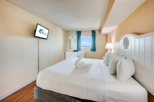 a bedroom with a large white bed with white pillows at Direct Oceanfront Unit Amazing Views with Pools in Myrtle Beach