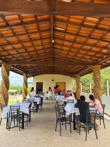 a group of people sitting at tables in a pavilion at Chalés Brisas dos lençóis in Barreirinhas