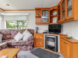 a living room with a couch and a television at Fron Dderw Caravan in Holyhead