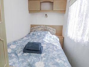 a bed in a small room with a blue blanket at Fron Dderw Caravan in Holyhead