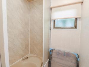 a bathroom with a shower with a toilet and a window at Fron Dderw Caravan in Holyhead +16 photos