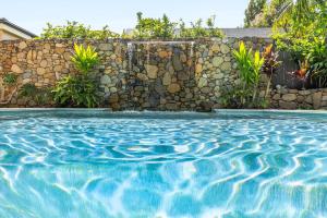 a swimming pool in front of a stone wall at Stone & Sand in Lennox Head