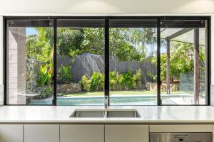 a kitchen with a sink and a window overlooking a pool at Stone & Sand in Lennox Head +15 photos