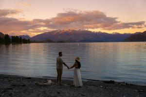 a bride and groom standing on the shore of a lake at Tasman Holiday Parks - Wanaka in Wanaka