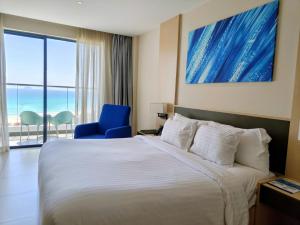 a hotel room with a bed and a blue chair at Oceanview Apartment at Arena Cam Ranh Resort in Thôn Hòa Ða +58 photos