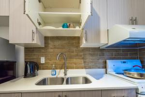 a kitchen with a sink and white cabinets at Pembroke suites in Toronto