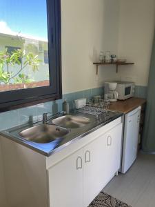 a kitchen with two sinks and a counter with a window at Rainbow beach Bungalow in Matura