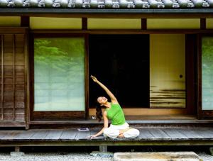 a woman sitting on a porch with her arm in the air at Oukai Villa Izumi in Izumi