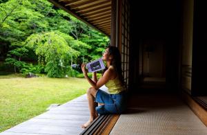 a woman sitting on a porch holding a book at Oukai Villa Izumi in Izumi +68 photos