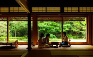 a group of three people sitting in a room with a window at Oukai Villa Izumi in Izumi