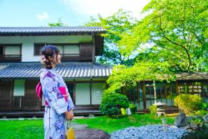 a woman in a kimono standing in front of a building at Oukai Villa Izumi in Izumi
