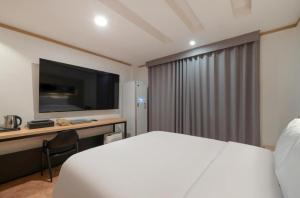 a hotel room with a bed and a television at Daejeon Dunsan ING Hotel in Daejeon