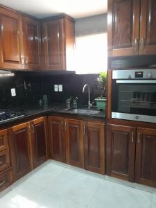 a kitchen with wooden cabinets and a sink and a microwave at Apart hotel GAVA in Encarnación