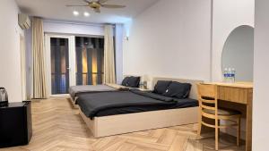 a bedroom with two beds and a table and a desk at The LH Homestay in Phú Quốc