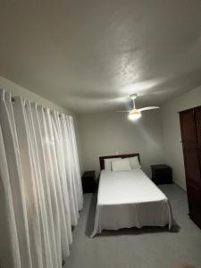 a bedroom with a white bed with white curtains at Casa na Natureza Próx Pomerode e Timbó in Rio dos Cedros